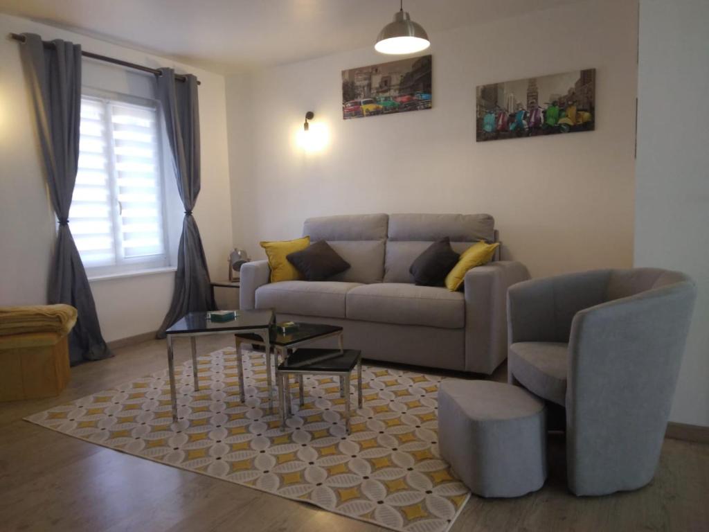 ein Wohnzimmer mit einem Sofa und einem Tisch in der Unterkunft Bel Appartement lumineux avec extérieur in Rosières-aux-Salines