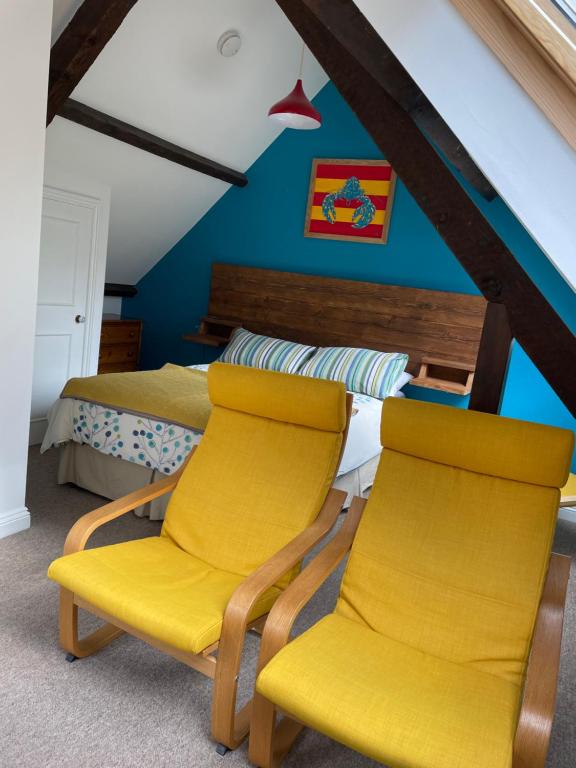 2 gelbe Stühle und ein Bett in einem Zimmer in der Unterkunft Wynards Farm in Winfrith Newburgh