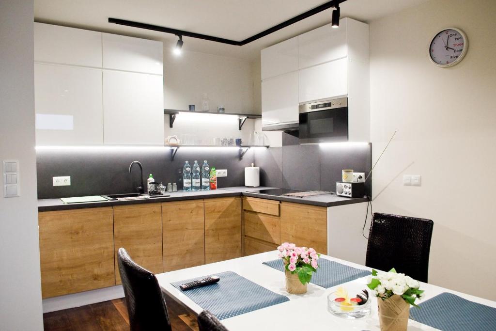 a kitchen with a table and a kitchen with white cabinets at Apartamenty Długa in Nowy Targ