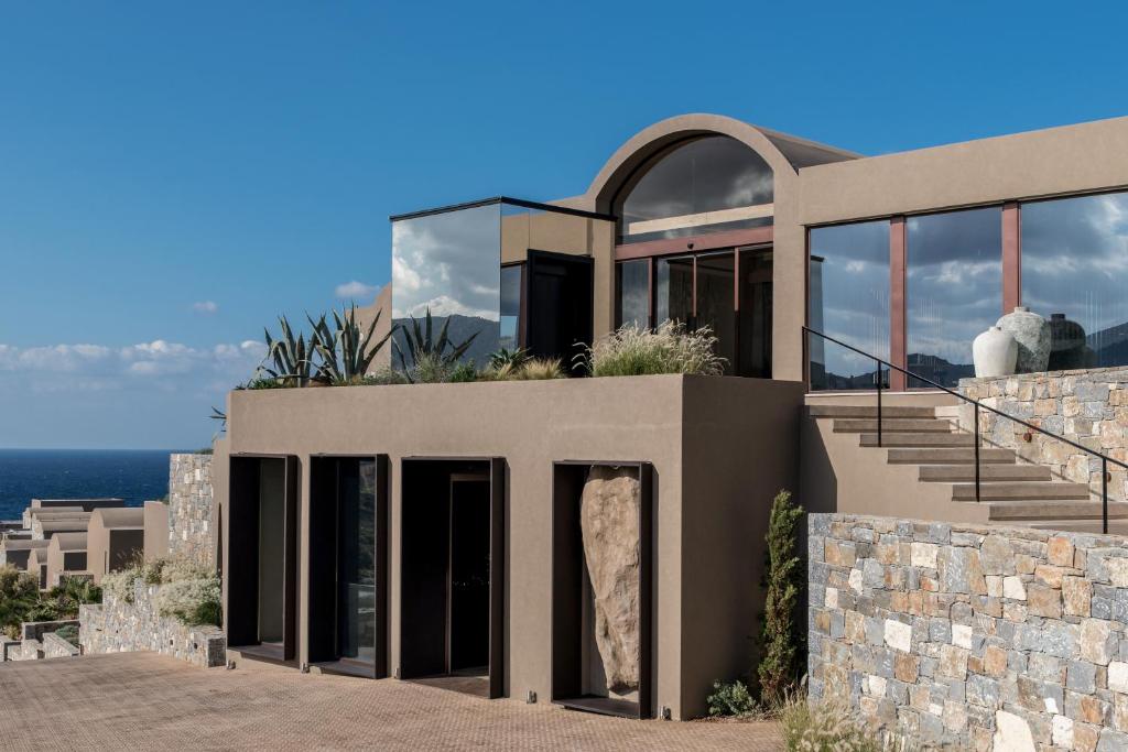 a large house with glass doors and a stone wall at Acro Suites - A Wellbeing Resort in Agia Pelagia
