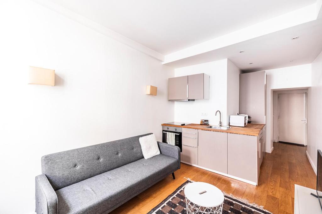 a living room with a couch and a kitchen at SAINT GERMAIN DES PRES - BAIL MOBILITE in Paris