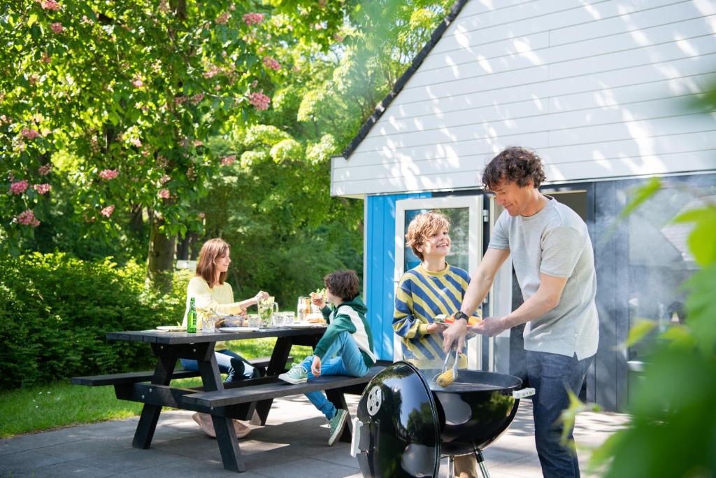 un grupo de personas sentadas en una mesa de picnic con una parrilla en Walibi Village, en Biddinghuizen