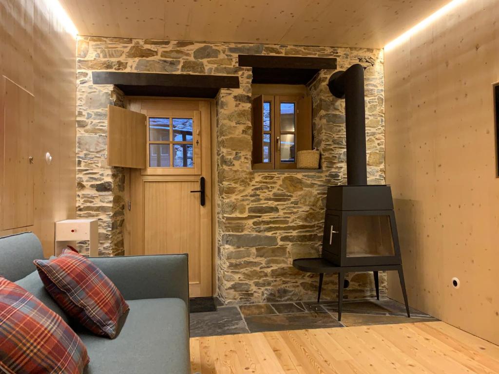 a living room with a stone wall with a wood stove at Casas do Talasnal in Lousã