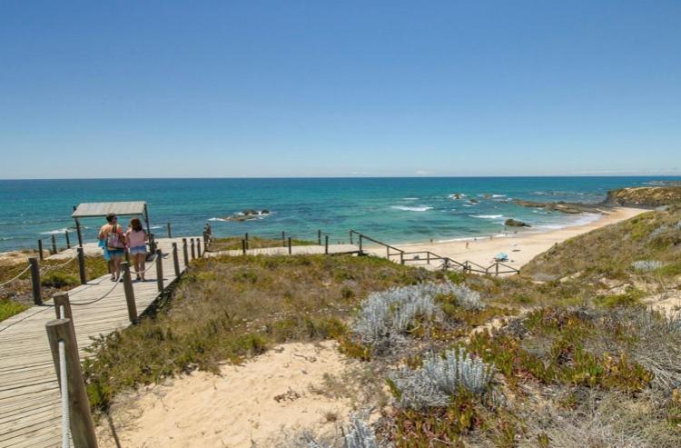 two people walking down a wooden path to the beach at Casa Isa By Natasha Gomes in Almograve