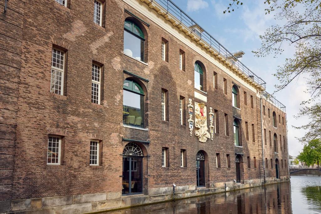 un gran edificio de ladrillo junto a un río en Hotel Arsenaal Delft, en Delft