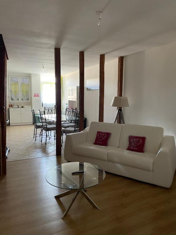 un soggiorno con divano bianco e tavolo in vetro di Maison à louer Les Roses ad Arconville