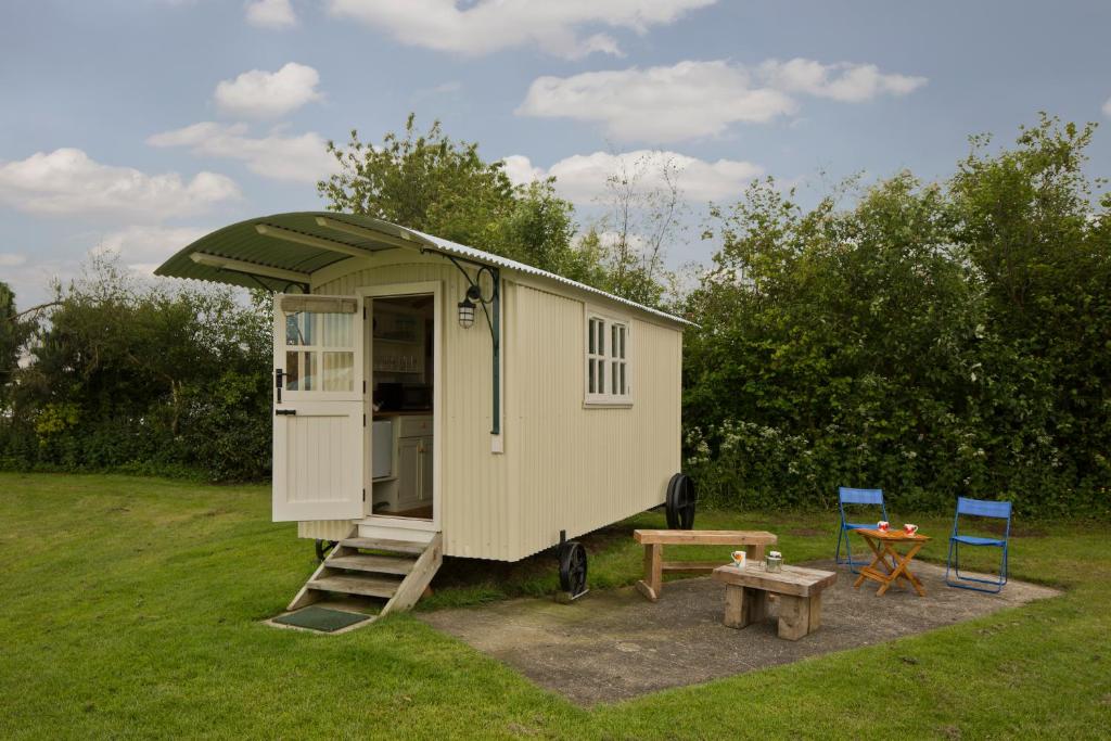a tiny house with a porch and a table and two chairs at Mill Farm Shepherds Hut in Great Driffield