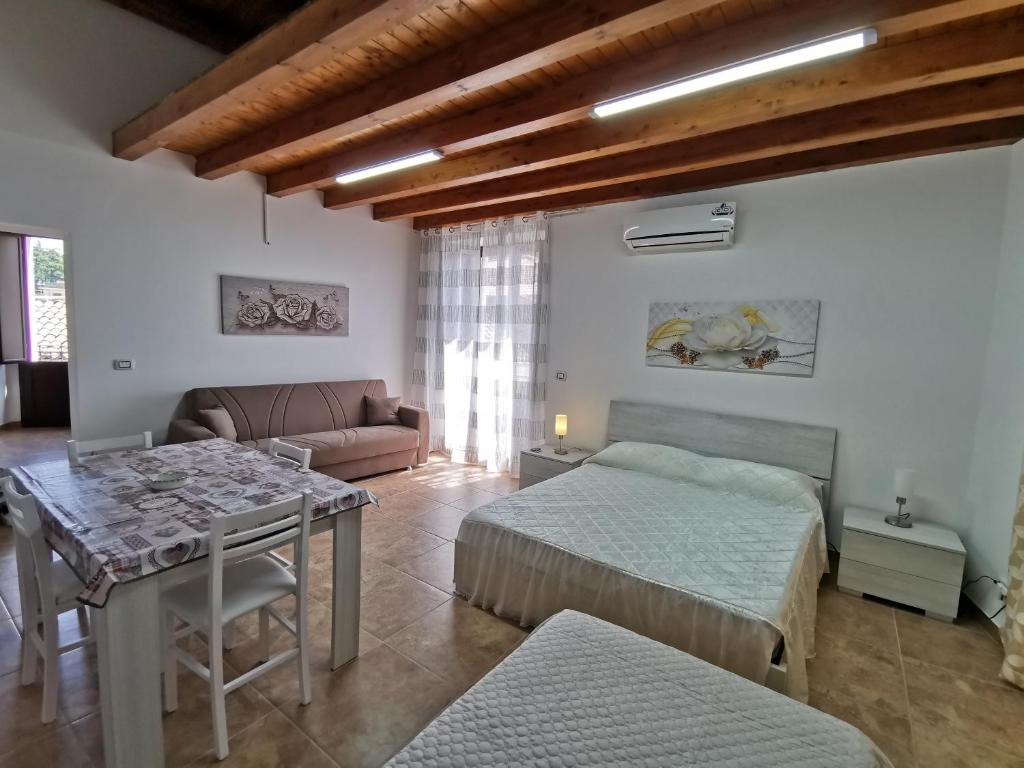 Sala de estar con 2 camas y mesa en Loft San Mauro, en Viagrande