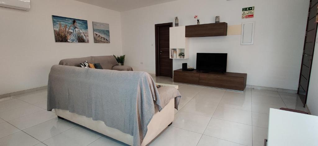 un soggiorno con un divano e una TV di Lorenza Letting Maisonette a Marsaxlokk