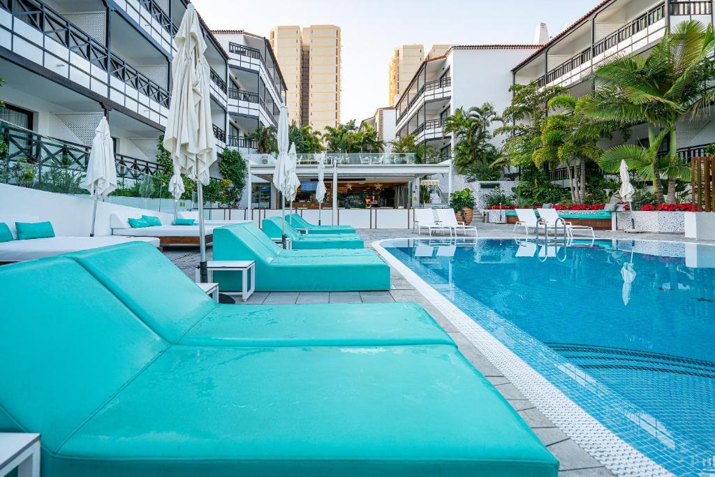 a large swimming pool with blue chairs and umbrellas at Vanilla Garden Boutique Hotel - Adults Only in Playa de las Americas