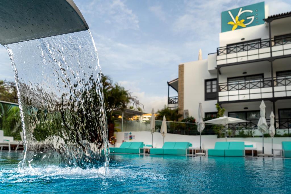 einen Brunnen in einem Pool vor einem Hotel in der Unterkunft Vanilla Garden Boutique Hotel - Adults Only in Playa de las Americas