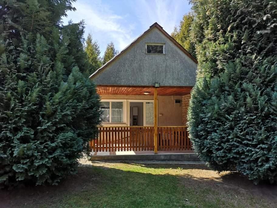 una casa con una valla de madera y dos árboles en Erdőszéli vendégház, en Dudar