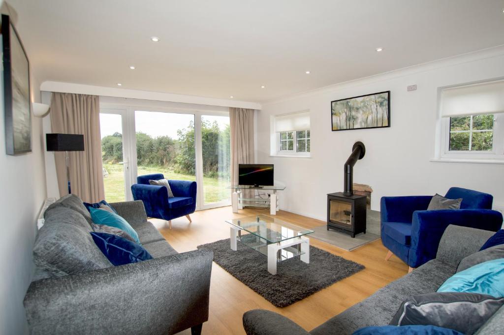 a living room with blue couches and a tv at Spacious 5 bed in the countryside, close to Frinton-On-Sea in Kirby Cross