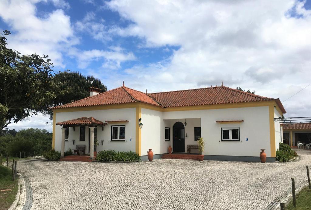 a white house with a red roof on a gravel road at Vagos Art.Lab in Vagos
