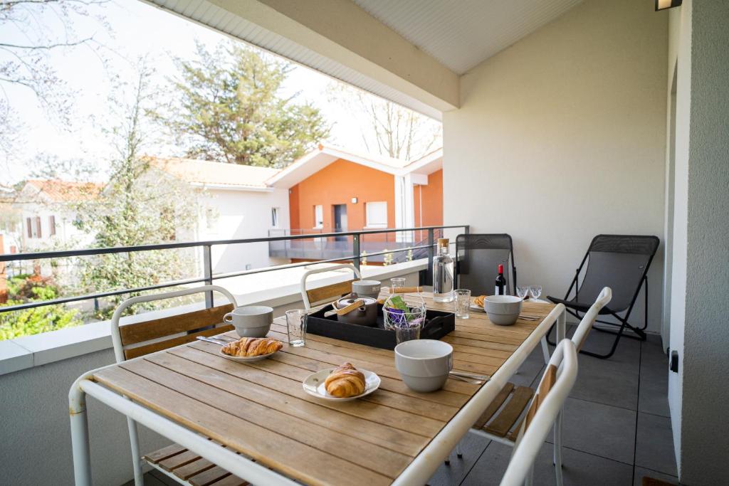 ラ・テスト・ド・ビュシュにあるSEAHORSE - Spacieux Appartement proche du port de la Testeの木製テーブルと食べ物を用意したバルコニー