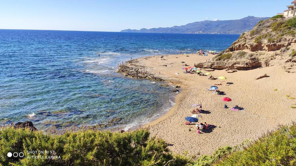 a beach with people laying on the sand and the water at Casa Sisina in Flussio