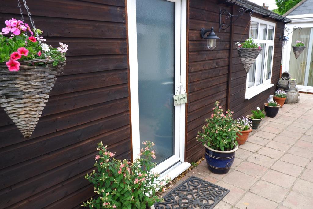 a house with potted plants on the side of it at The Garden Suite Holt in Holt