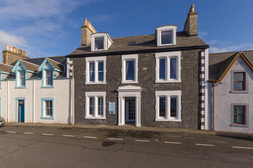 a large brick house with white windows on a street at Carlton House Portpatrick in Portpatrick