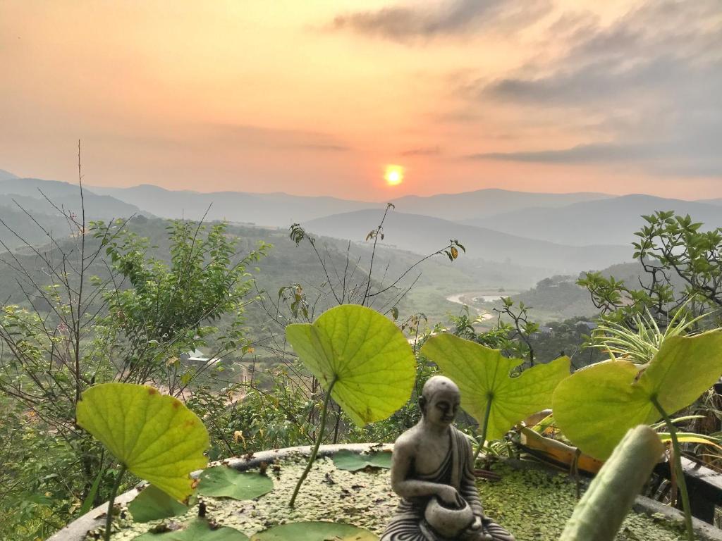 a statue of a woman sitting on a hill with green leaves at Midori Coffee Farm in Da Lat
