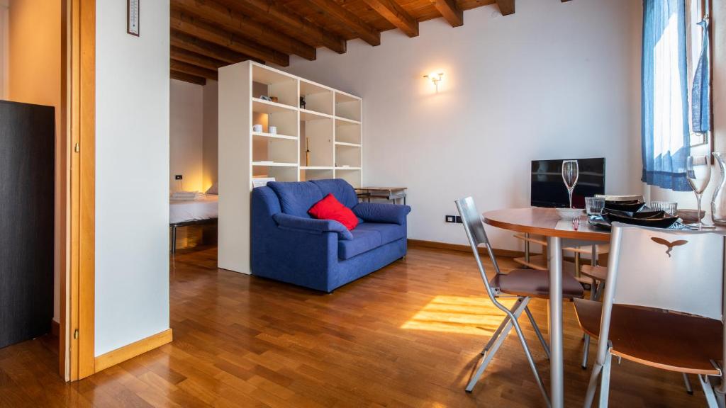 Una sala de estar con un sofá azul y una mesa. en Galilei 41, en Udine