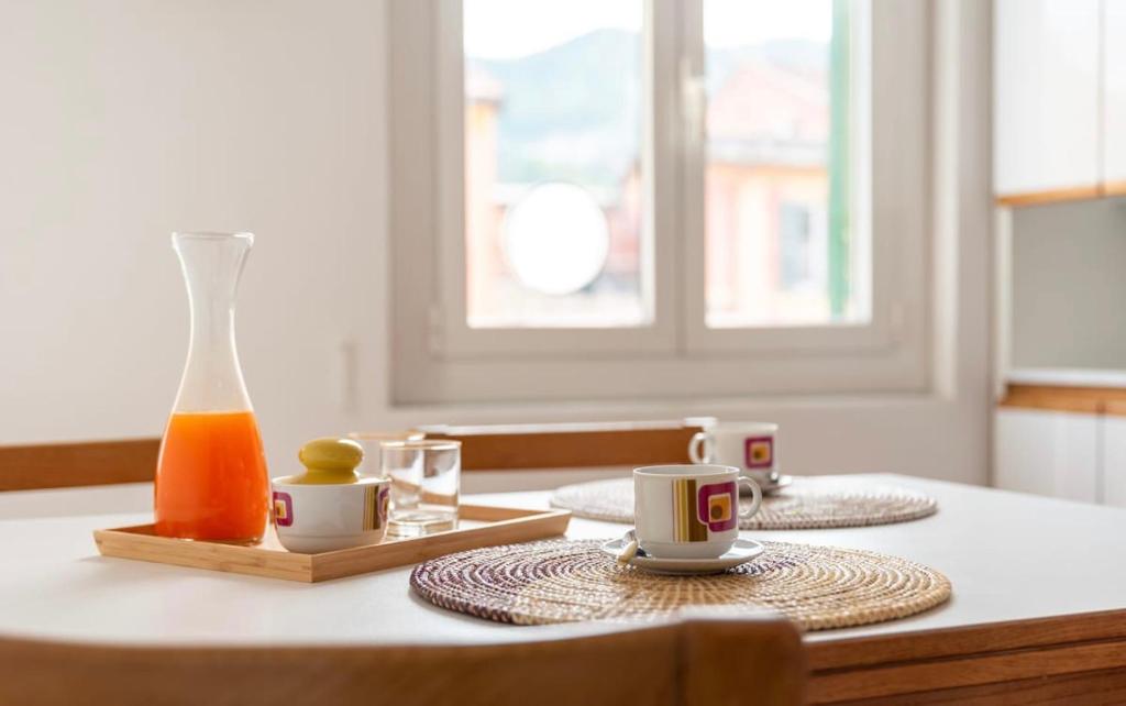 una mesa con dos tazas y una botella de zumo de naranja en Henry's House, en Santa Margherita Ligure
