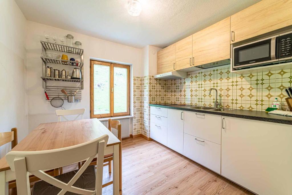 cocina con armarios blancos y mesa de madera en Casa Mirabella, en Sottoguda