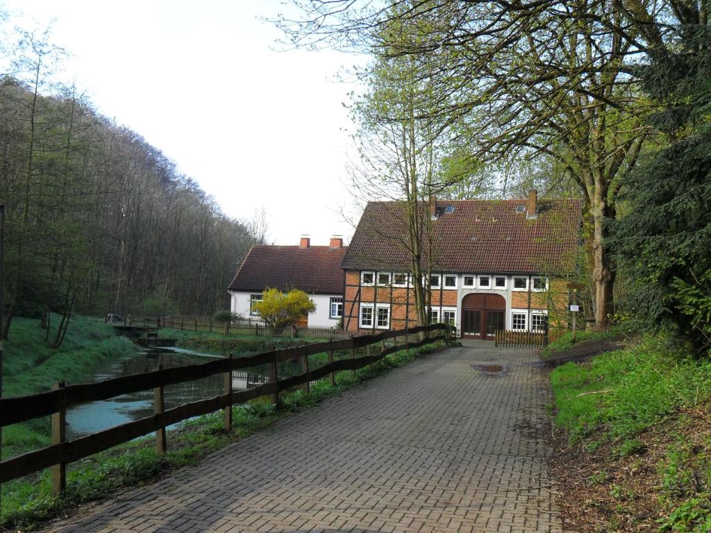 a house with a fence next to a river at Höllenmühle Bed & Breakfast at the Mill Pond in Hessisch Oldendorf