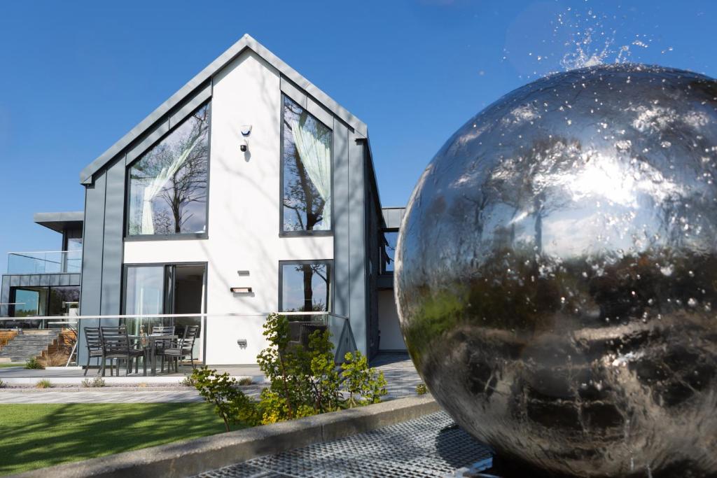 uma grande bola de metal em frente a uma casa em Dafarn Newydd Studio em Llangefni