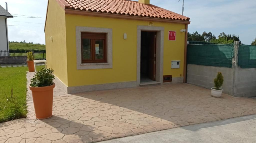 uma pequena casa amarela com uma porta num quintal em O CORPIÑO DE CHORENTE em Muxia