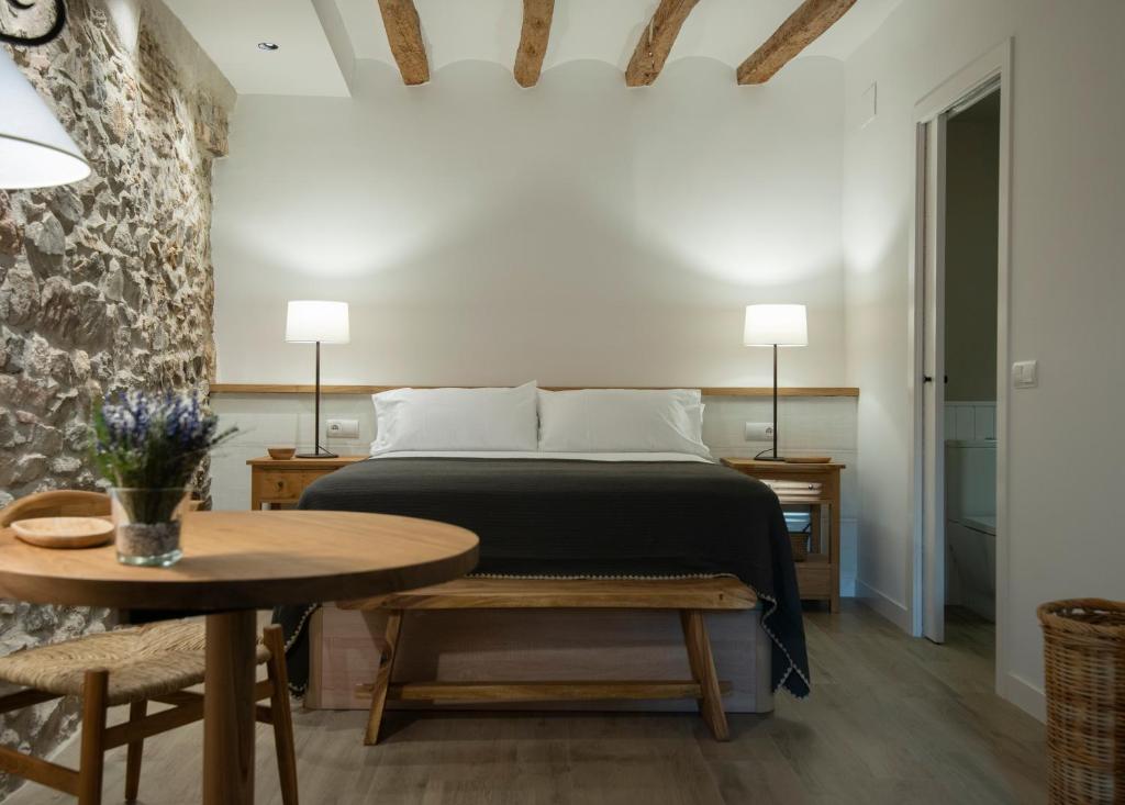 1 dormitorio con cama, mesa de madera y sidra de mesa en L' Alzina, en Falset