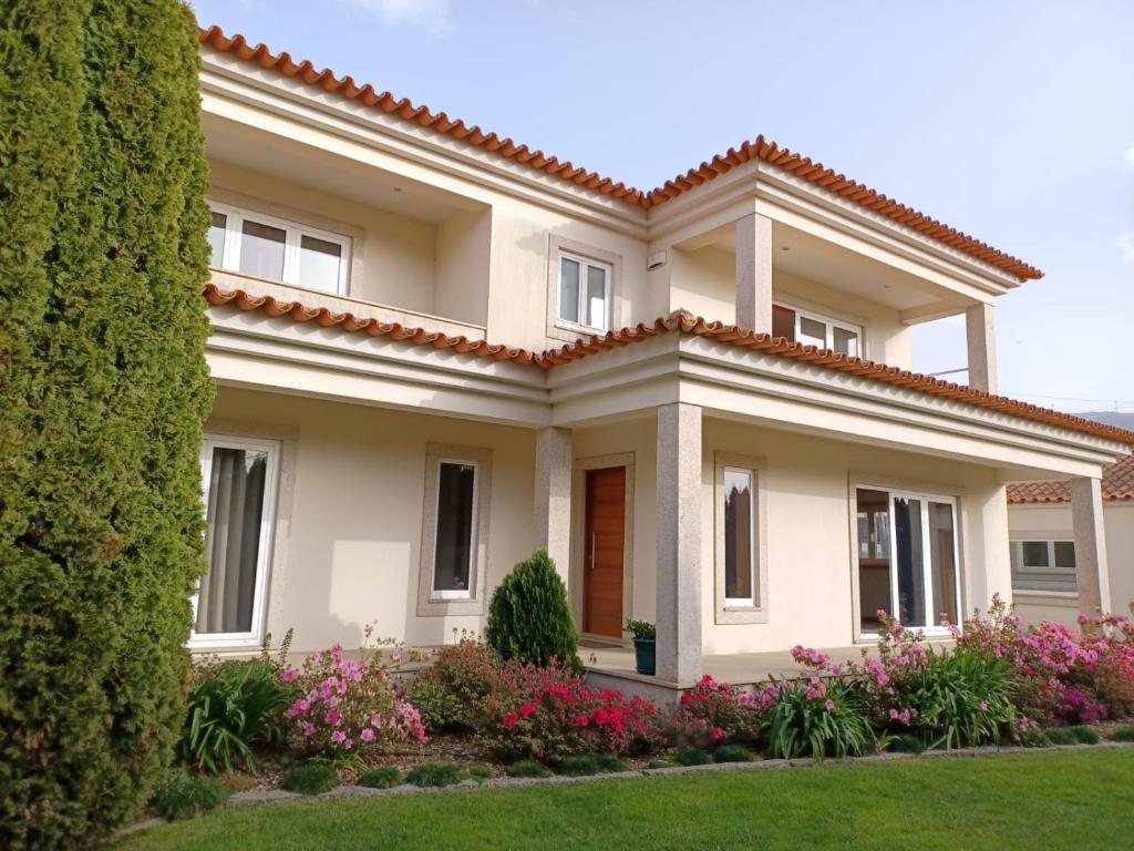 een groot huis met bloemen ervoor bij Vivenda do Parque Arouca in Arouca