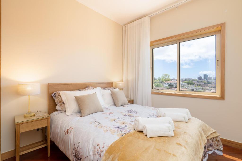 a bedroom with a large bed with a window at Lovely Bright Flat - Instaworthy City View in Vila Nova de Gaia