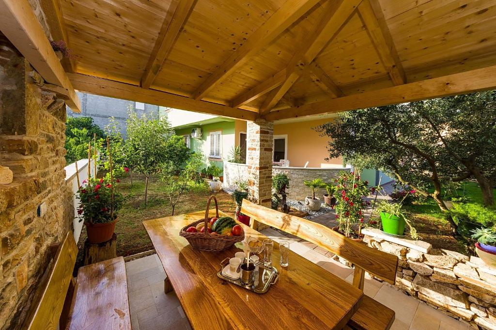 a wooden bench on a patio with a wooden roof at Apartmani Vanja in Zadar
