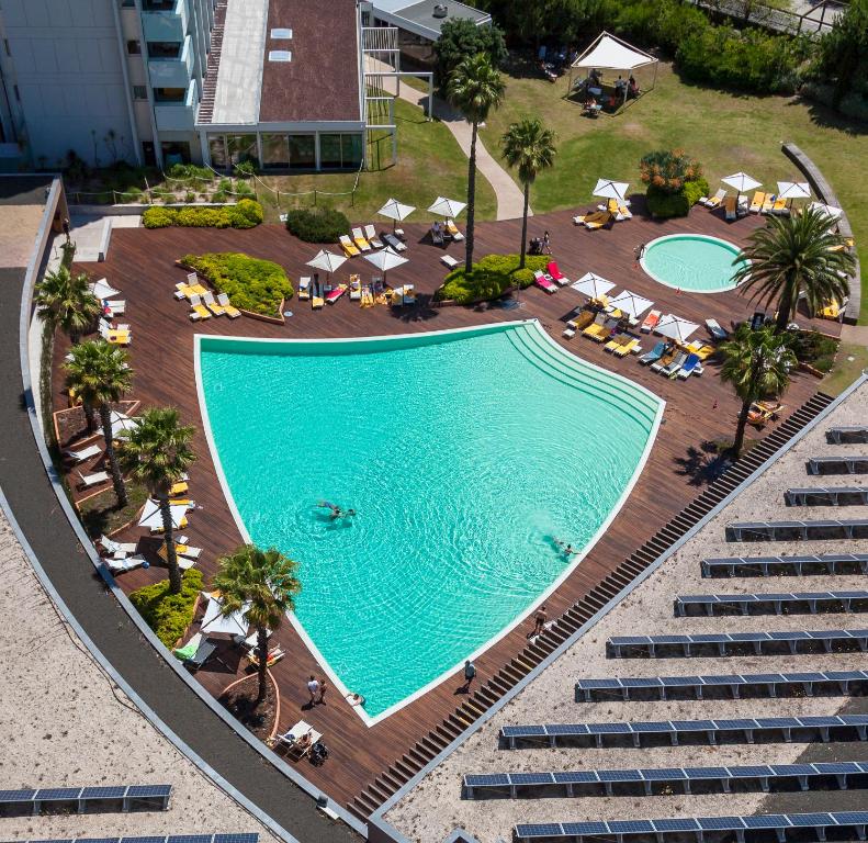una vista aérea de una piscina con sillas y palmeras en Aqualuz Troia Rio by The Editory en Tróia