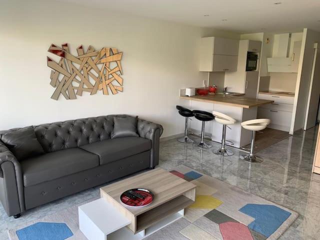 un salon avec un canapé noir et une cuisine dans l'établissement Studio Résidence Le Tanit, à Antibes