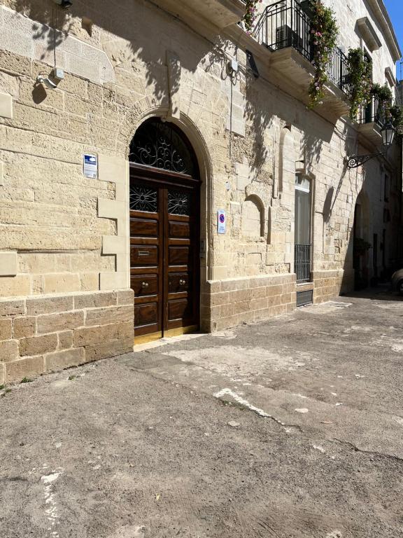 a brick building with a wooden door and a balcony at B&B Regina Maria in Lecce