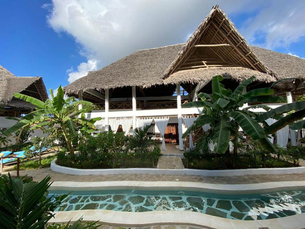 a resort with a swimming pool and a building at Paka House-Rafiki Village in Watamu