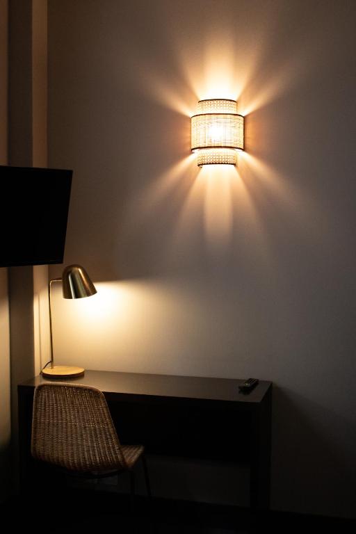 a light on a wall with a desk and a lamp at Hotel Molière in Cannes