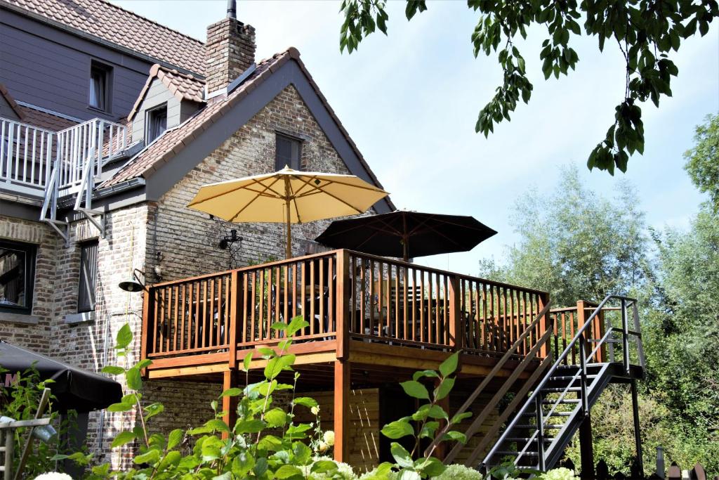 una terraza con dos sombrillas en una casa en B&B De Dubbelmolen, en Tongeren