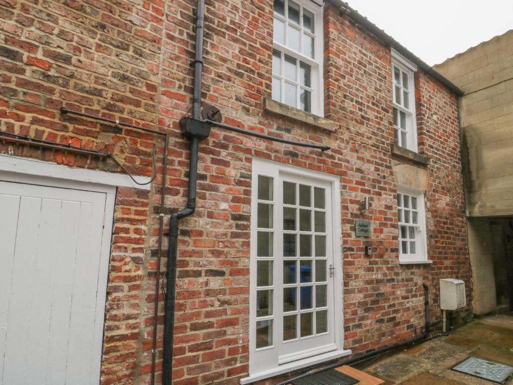 a brick building with a white door and a garage at Ashben Cottage in Whitby