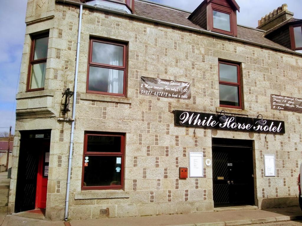 a brick building with a white marrow added sign on it at White Horse Hotel in Strichen