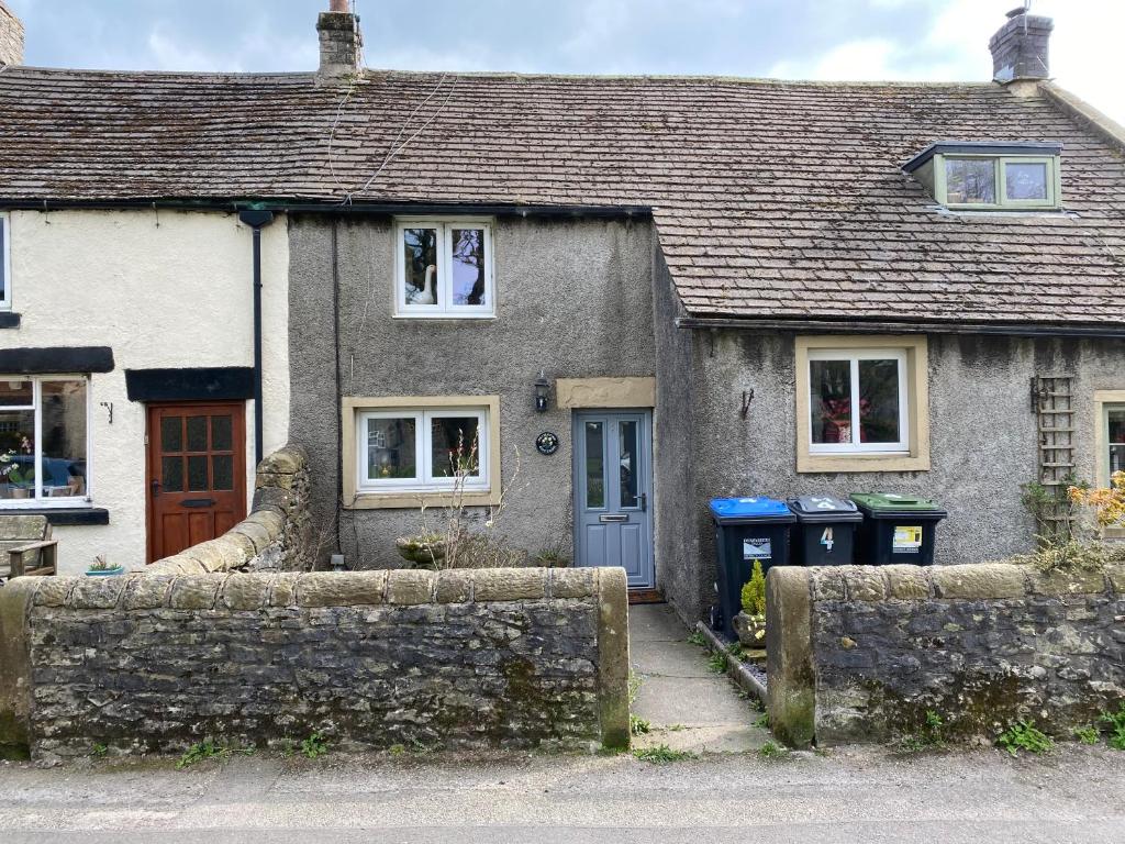 a house with two trash cans in front of it at Primrose cottage in Tideswell