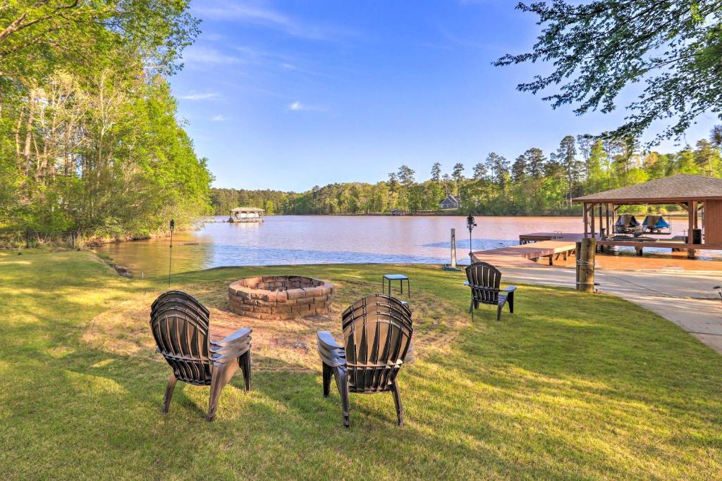three chairs sitting in the grass near a lake at Chic Lake Sinclair Retreat with Dock and Hot Tub! in Resseaus Crossroads