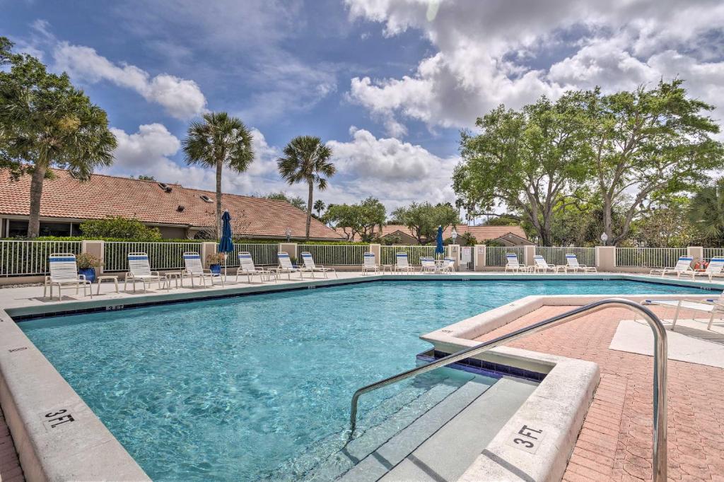 a swimming pool with chaise lounge chairs at Palm Beach Gardens Condo with Pool and Beach Access in Palm Beach Gardens