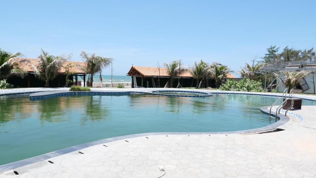 einen Pool in einem Resort mit dem Meer im Hintergrund in der Unterkunft Green Star Premium Resort - Mui Ne - Formerly Hung Thinh Resort in Ấp Long Sơn