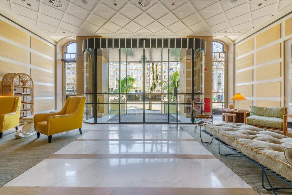 a lobby with yellow chairs and a large window at The Editory Boulevard Aliados Hotel in Porto