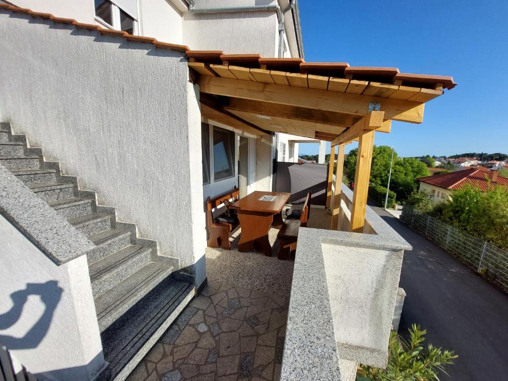 een houten pergola aan de zijkant van een huis bij Mely Apartment in Krk