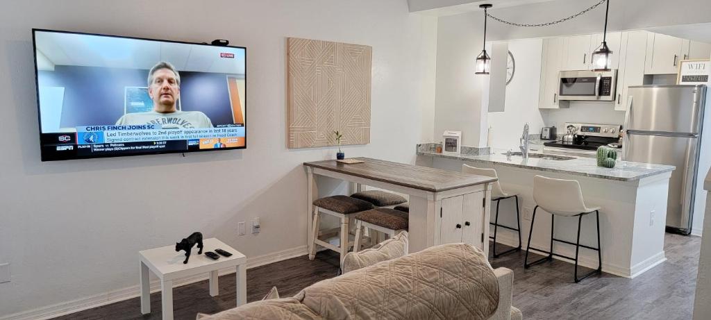 eine Küche und ein Wohnzimmer mit einem großen TV an der Wand in der Unterkunft Discover Luxury Condo Steps Away from Celebration Pointe and I-75! in Gainesville