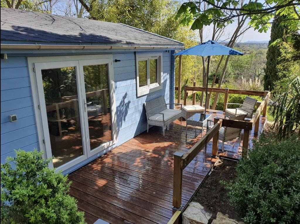 a wooden deck with two chairs and an umbrella at Adorable chalet avec jacuzzi privatif in Aix-en-Provence