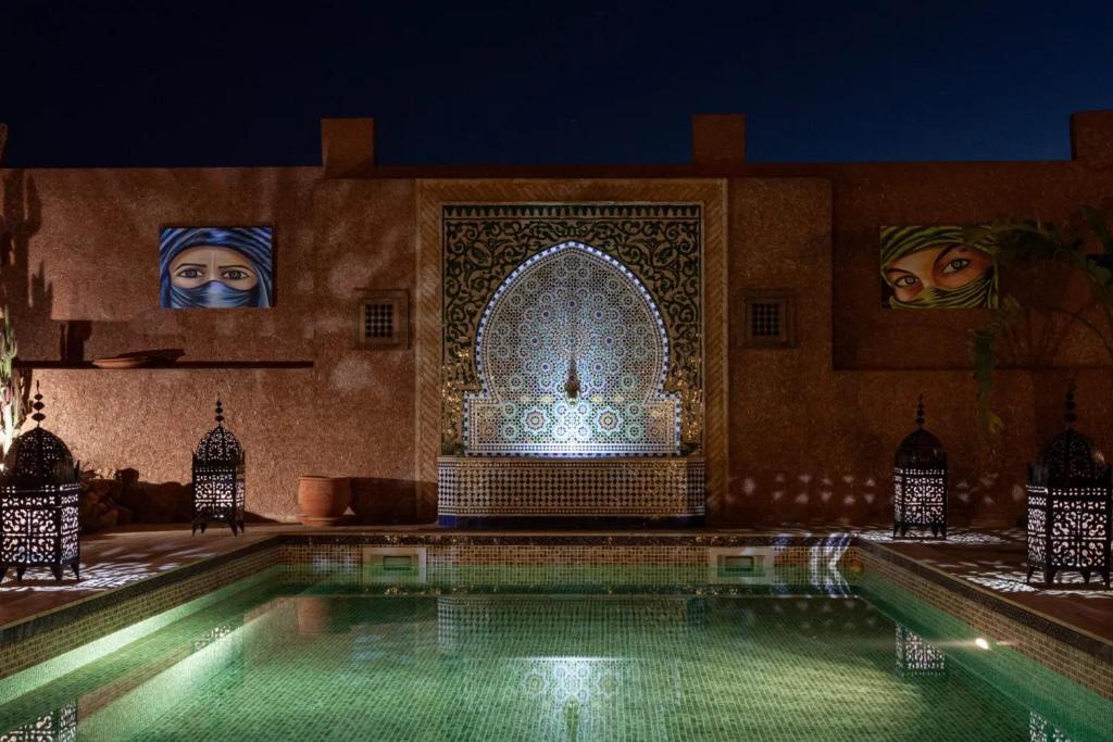 una piscina frente a un edificio por la noche en Riad SOUS LES ETOILES, en Sidi Bibi